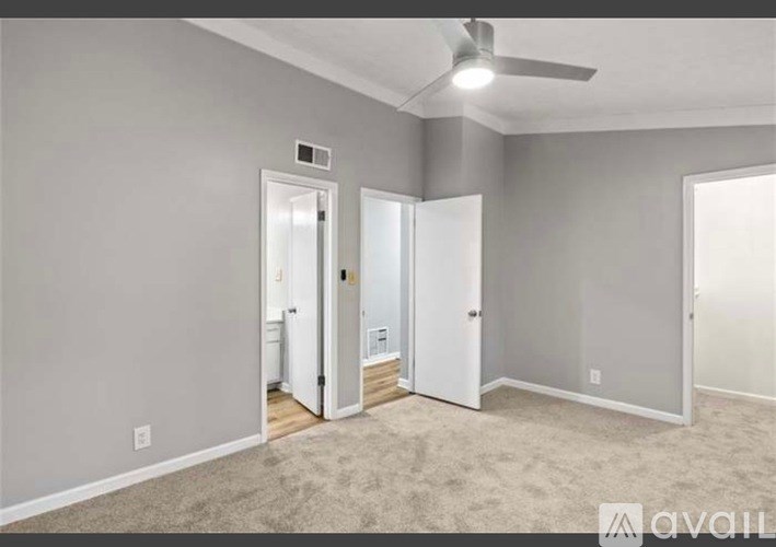 A room with a carpeted floor and a ceiling fan.