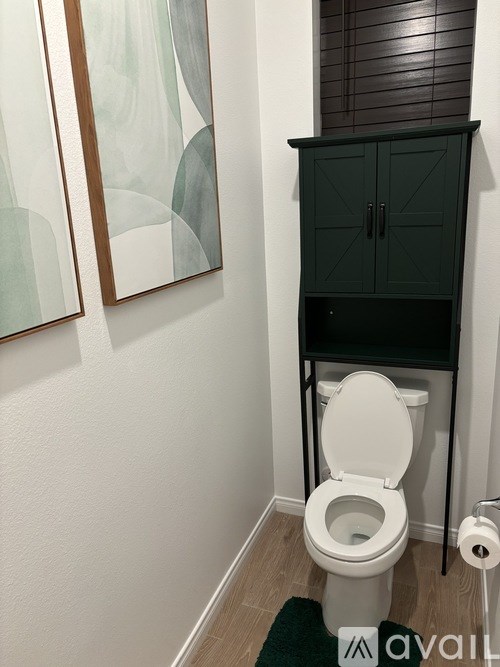 A white toilet in a bathroom with a cabinet above it.