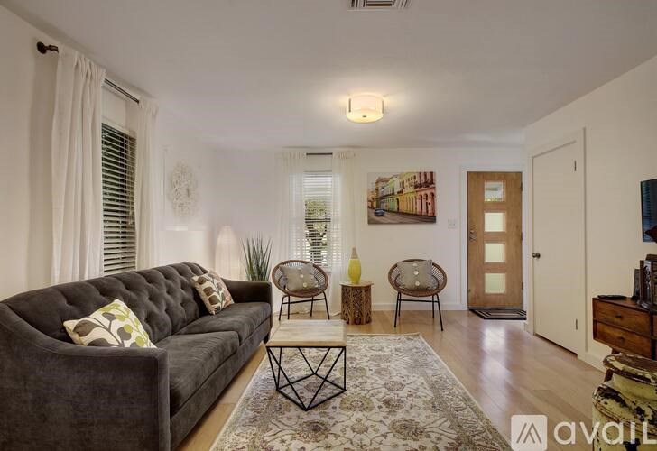 A living room with a grey couch, a coffee table, and a rug.