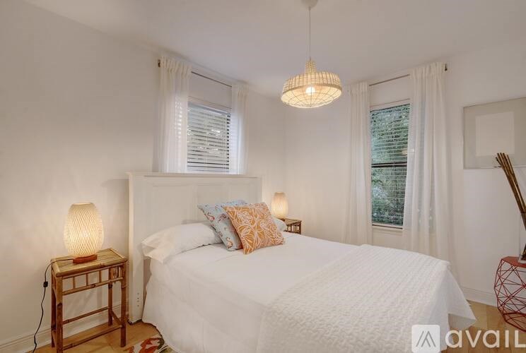 A bedroom with a white bed and a hanging light fixture.