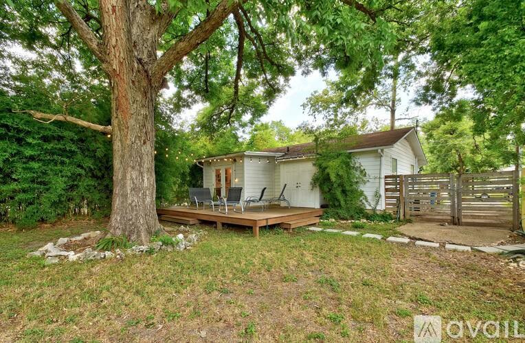 A tree stands in front of a white house.