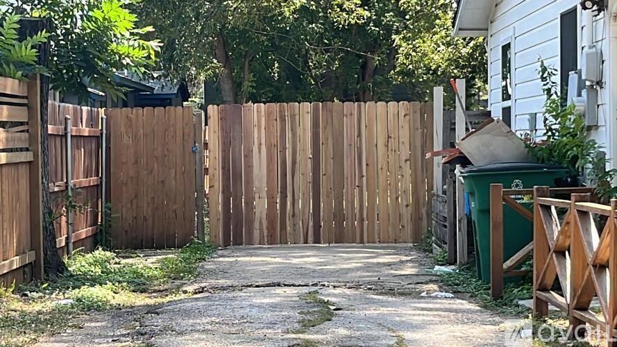 A wooden fence and gate in front of a white house.
