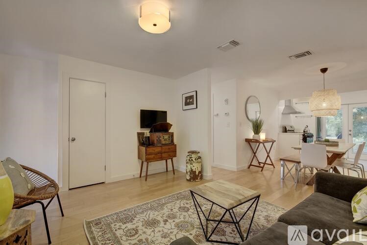 A living room with a rug, a sofa, a chair, a coffee table, a TV, and a dining table.