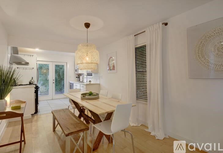 A dining room with a table set for two and a white chair.