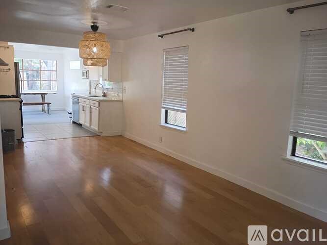 A spacious room with wooden floors and white walls.