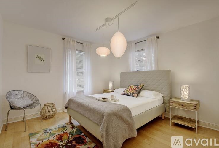 A bedroom with a bed, a chair, and a table with a lamp on it.