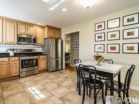A kitchen with a table and chairs in front of a fridge and oven.