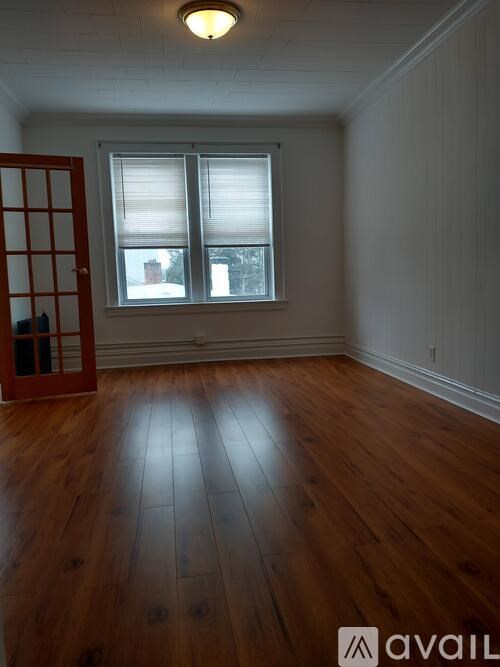 A room with wooden floors and a window with blinds.