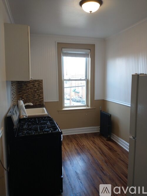 A room with a black fridge and a window.