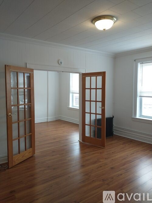 A room with wooden floors and two open doors.