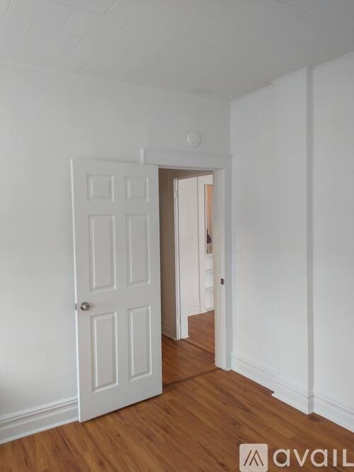 A white door is in a room with wooden floors.