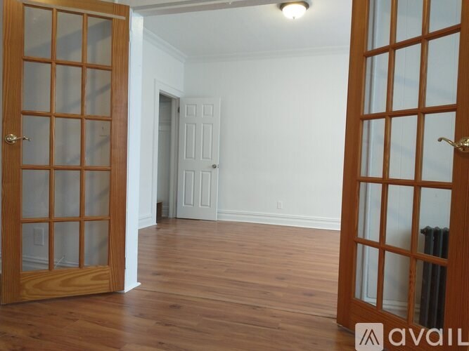 A room with wooden floors and a door on the left.