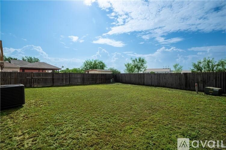 A backyard with a wooden fence and a grassy area.