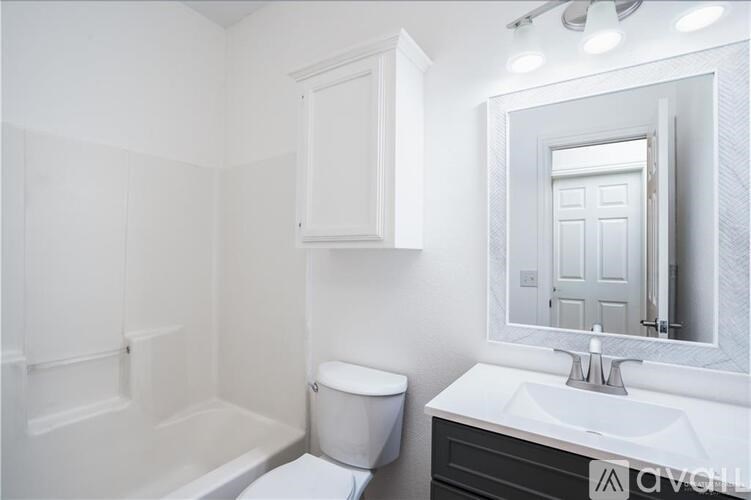 A white bathroom with a toilet, sink and mirror.
