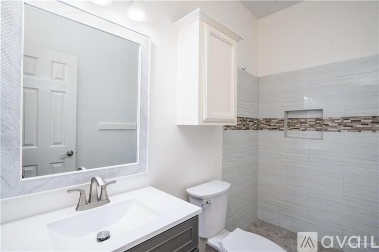 A white bathroom with a toilet, sink, and mirror.