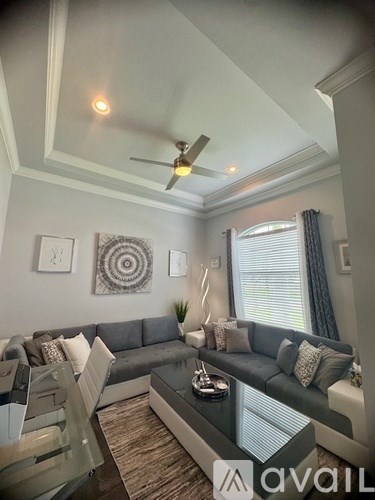 A living room with a grey couch and a glass coffee table.