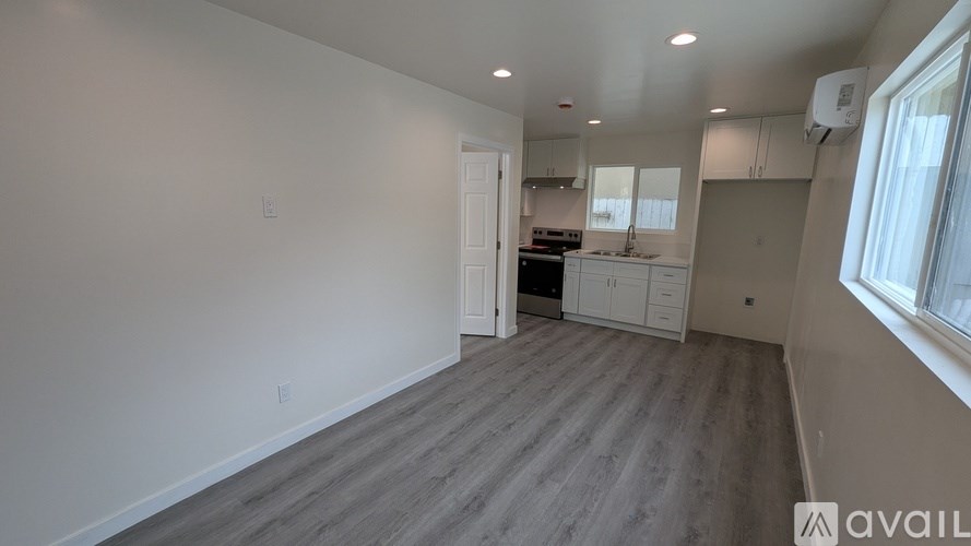 A spacious room with a kitchen area in the background.