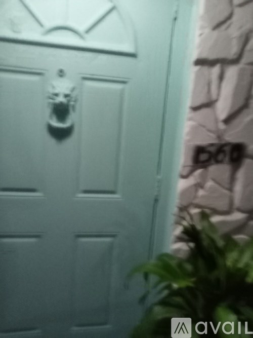 A white door with a decorative handle and a stone wall.