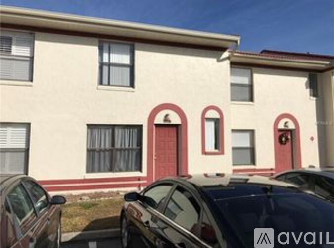 A beige building with red trim and a row of parked cars.