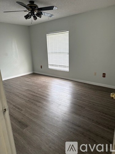A room with a ceiling fan and a window with blinds.