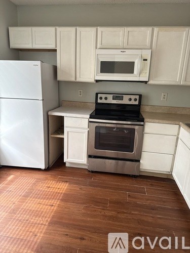 A kitchen with a white fridge, microwave and oven.