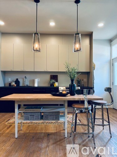 A kitchen with a wooden table and chairs, and pendant lights hanging above it.