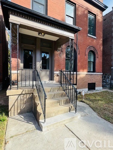A red brick building with a black iron railing on the stairs.