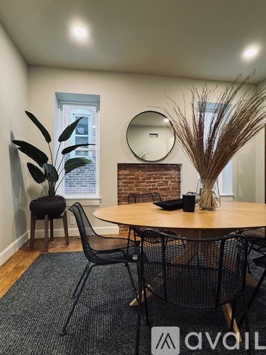 A room with a round table and chairs with a mirror and a plant on it.