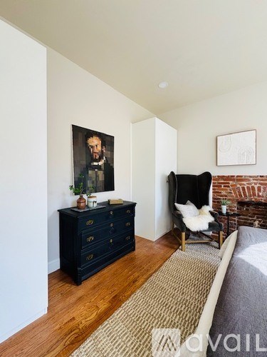 A room with a black dresser and a chair with a white cushion.