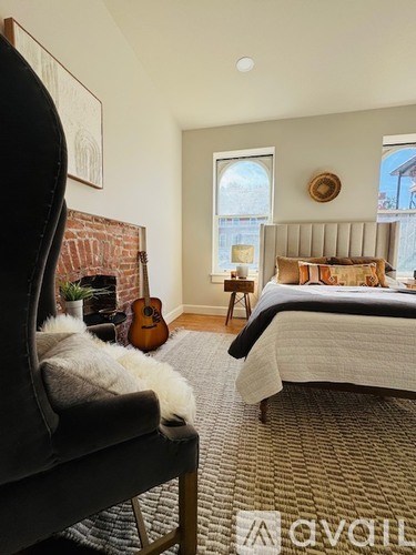 A bedroom with a bed, chair, and guitar.