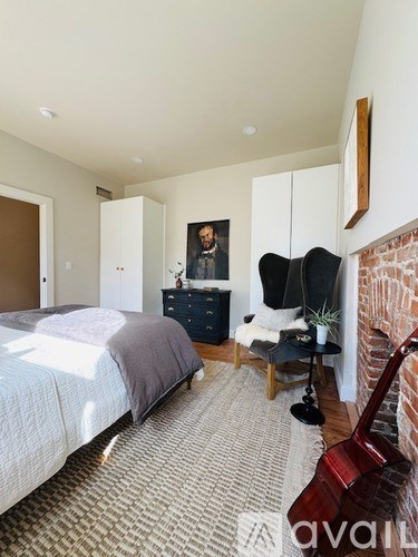A bedroom with a bed, a chair, a dresser, and a guitar.