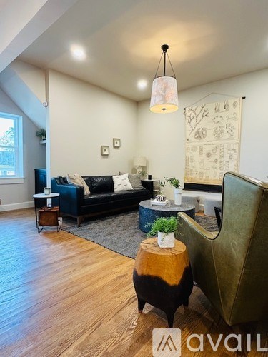A living room with a black couch and a wooden floor.