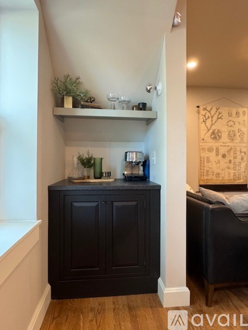 A black cabinet with a shelf above it and a bed in the background.