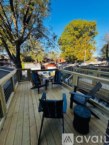 A wooden deck with chairs and a table is surrounded by trees.
