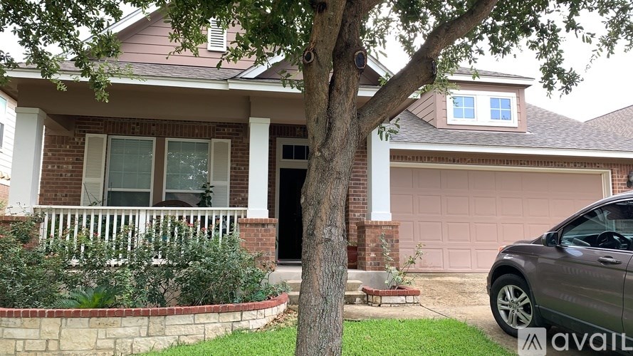 A house with a tree in front of it and a car parked in the driveway.