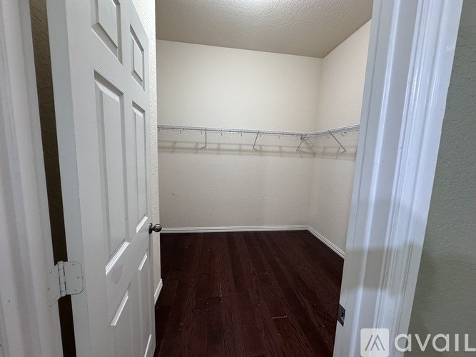 A small, empty room with a wooden floor and white walls.