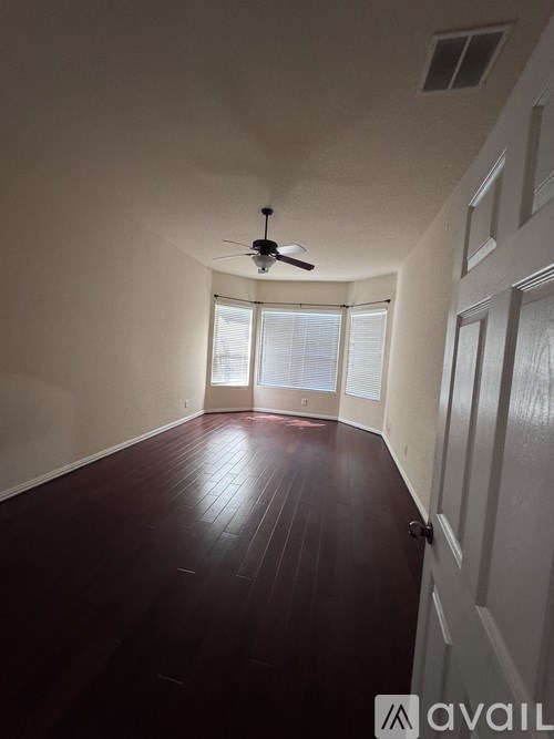 A room with a ceiling fan and wooden flooring.