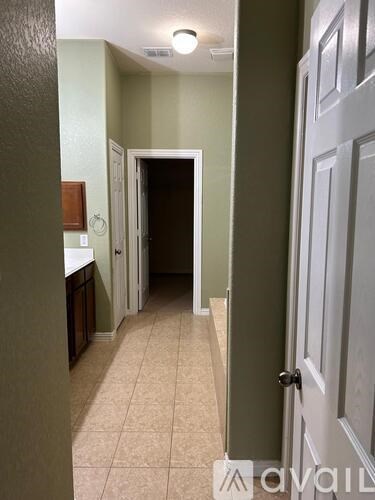 A hallway with a door on the right and a light switch on the wall.