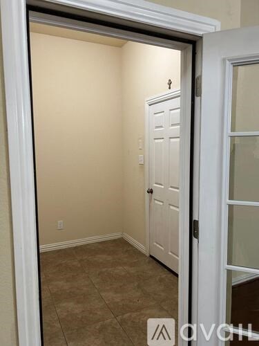 A white door is open to a room with a brown floor.
