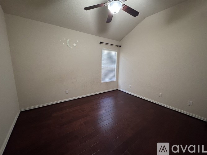 A room with a ceiling fan and a window with blinds.