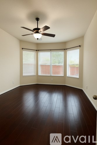 A room with a ceiling fan and wooden flooring.