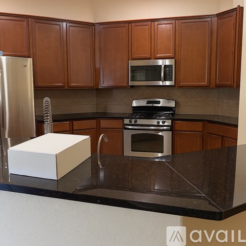 A kitchen with brown cabinets and a black countertop.