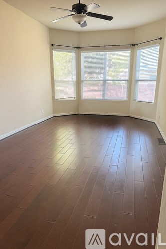 A room with a ceiling fan and sliding glass doors.
