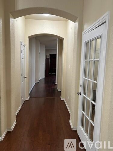 A hallway with white doors and a wooden floor.