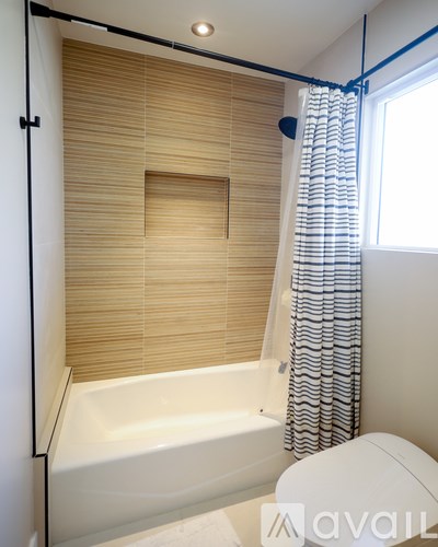 A bathroom with a white tub and a window with blinds.