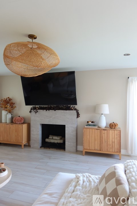 A living room with a fireplace and a hanging rattan lamp.