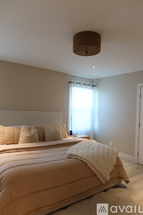A bedroom with a large bed and a window with curtains.