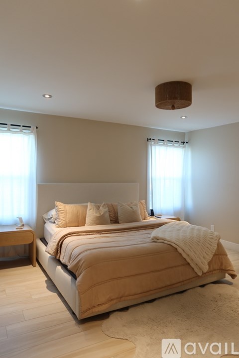 A bedroom with a large bed and a window with curtains.