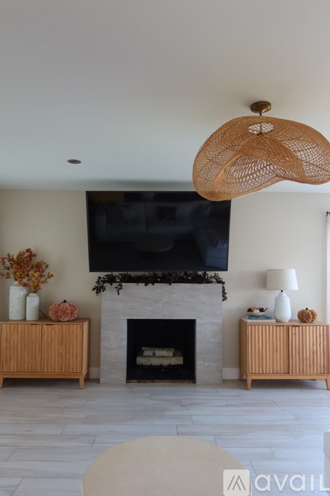 A living room with a fireplace and a television mounted above it.