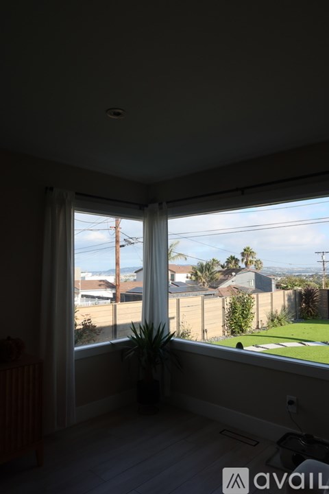 A room with a window overlooking a residential area.